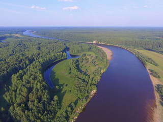 Bends of the river in the coniferous forest and blue sky. Sysola river, Komi Republic, Russia. View from top