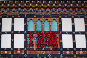 Peppers drying hanging out of a window in a bhutanese building, with a traditional architecture.