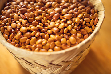 Exotic colorful mexican beans on wicker basket. Top view of legumes. Concept of beans food. Exotic beans on wooden table. Rustic background of beans. Colorful legumes on rustic setting.