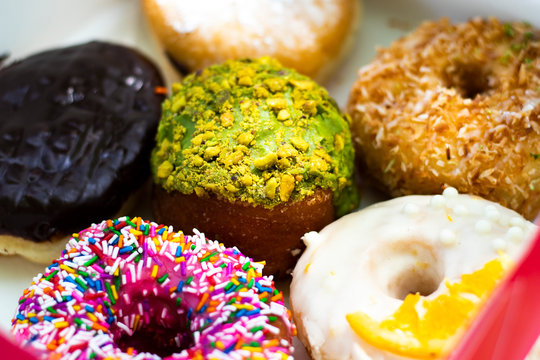 Extreme close up of colorful assorted donuts in a pink box, sugar rush and horizontal image
