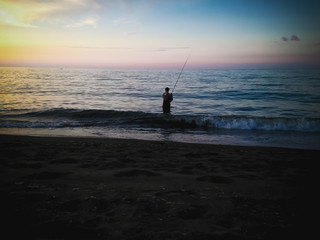Sunset Shine Beach Horizon View With Man Fishing In The Evening At The Village, Seririt, North Bali, Indonesia