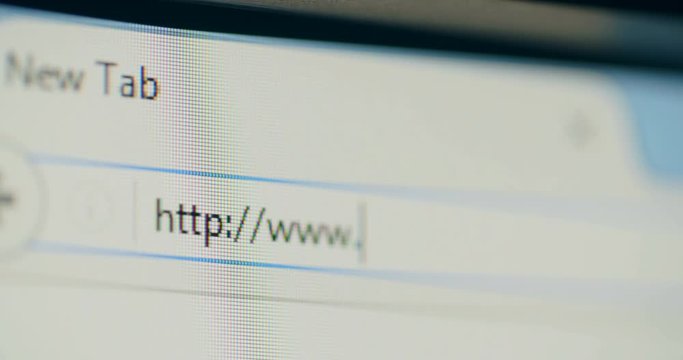 Handheld, extreme closeup shot of a computer screen with an open browser - typing an Internet address.