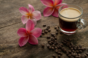 Obraz na płótnie Canvas Cup coffee and frangipani (plumeria) on textured wooden table.