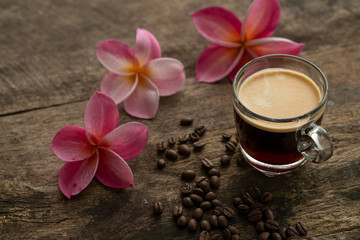 Obraz na płótnie Canvas Cup coffee and frangipani (plumeria) on textured wooden table.