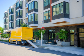 Delivery big rig semi truck with box trailer and sliding ramp standing on the city street near a...