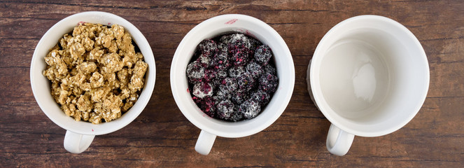 Three white single serving bowls with blackberry crumble dessert, on a wood background
