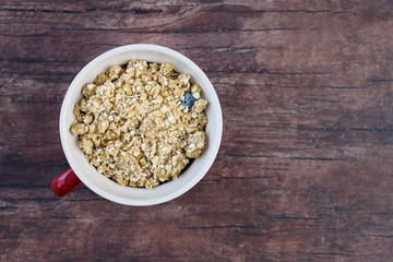 White single serving bowl with frozen blueberries and crumble topping, wood background
