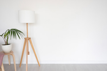 floor lamp and stool with indoor flower on the background of a white empty wall. space for text.