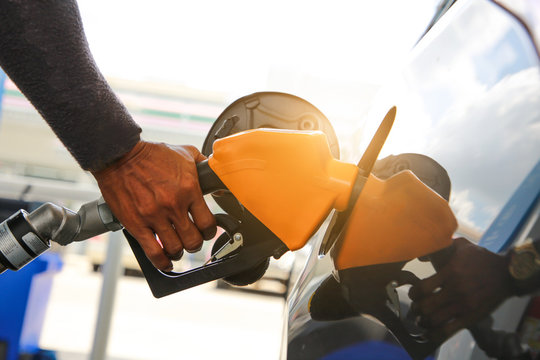 Man pumping gasoline fuel in car at gas station.