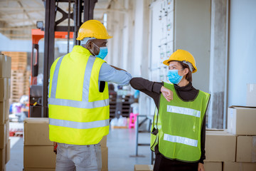 Industry workers under discussion said hello in new normal concept at factory warehouse ,they wearing safety uniform hard hat and medical mask for protect virus.