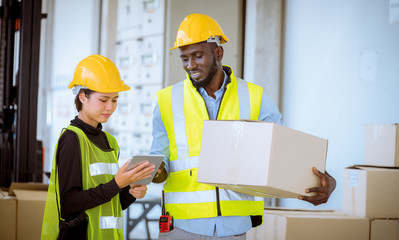 Industry workers helping to move produce boxes for folklife truck to keep on factory warehouse ,they look  produce detail on tablet with factory background.