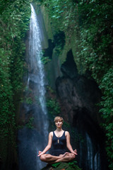 Fototapeta na wymiar Yoga practice and meditation in nature. Woman practice near waterfall.