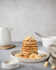 stack of oatmeal pancakes with bananas and nuts. healthy breakfast. gray background, vertical image