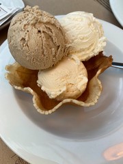 Tasty ice-cream is on the white plate on the table