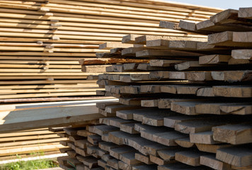 Wooden beam, stacked at construction site. Wooden planks, lining, boards for construction works in the sawmill. Timber mill.
