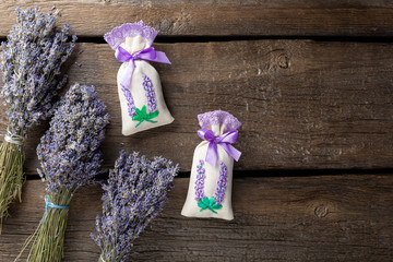 sachet with dried lavender, decorated with ribbon and lavender in bunches. dark wooden background. Fragrant dried flowers. top view. copy space