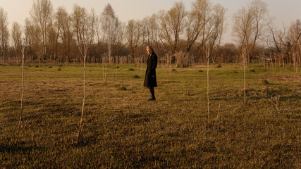 Lonely girl in black stands in a field