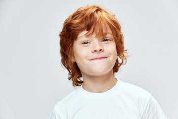 Red-haired boy with freckles on his face close-up white t-shirt cropped 