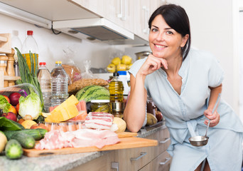 Portrait of cheerful female who is readying for cooking new recipe at home.