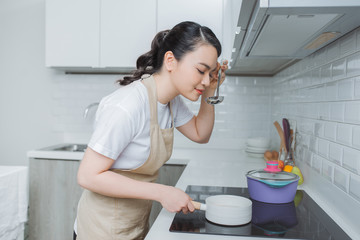 Young Woman Tasting Food With Spoon In Kitchen