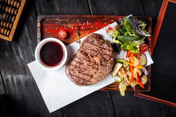 Grilled juicy steak with sauce and salad