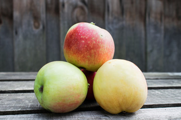 in the center of the photo is a pile of apples on a wooden table