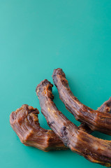 Dried turkey neck on a turquoise background.