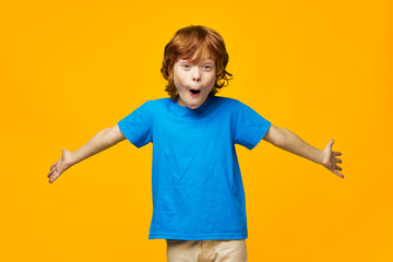 Cheerful boy smiling at camera gesture with hands to hand surprise childhood blue t-shirt 