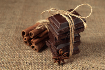 Tied pieces of chocolate with star anise and cinnamon on burlap napkin