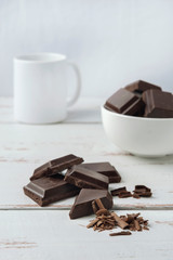 A few pieces of chocolate with chocolate shavings on white Provence style table