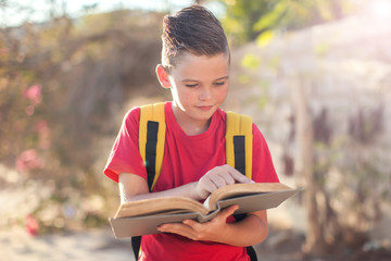 Pupil with book and magnifying glass outdoor. Back to school. Children and education concept