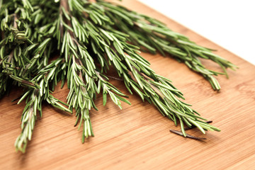 Rosemary branches lie on a wooden Board. Concept of various herbs and seasonings for meat, cooking delicious food using seasonings