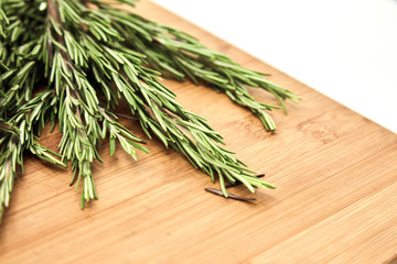 Rosemary branches lie on a wooden Board. Concept of various herbs and seasonings for meat, cooking delicious food using seasonings