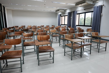 Empty school classroom with many wooden chairs. Wooden chairs in classroom. Empty classroom with vintage tone wooden chairs. Empty college classroom. Education stock photo.