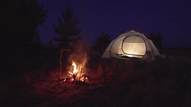 Bonfire near an empty tent at night. Travel concept 4K