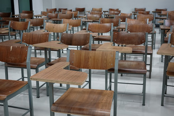 Empty school classroom with many wooden chairs. Wooden chairs in classroom. Empty classroom with vintage tone wooden chairs. Empty college classroom. Education stock photo.