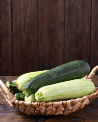 Raw zucchini. Zucchini in a basket on a brown wooden table
