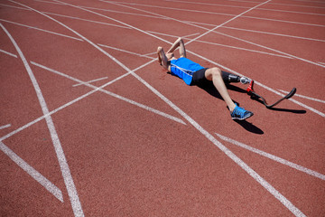 Adaptive sportsman laying on the running track outdoor after failure