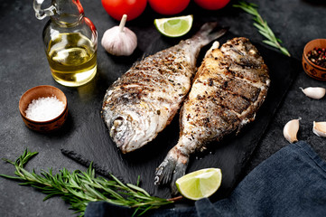 grilled dorado fish with ingredients on stone background