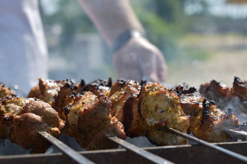 man fries meat on the grill on skewers. Camping