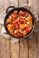 Delicious baked peppers with rice, meat, cheese and tomato gravy close-up in a frying pan on the table. vertical top view from above
