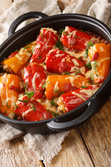 Baked stuffed peppers with rice, meat, cheese and tomatoes close-up in a frying pan on the table. vertical