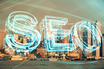 SEO hologram on city view with skyscrapers background double exposure. Search optimization concept.
