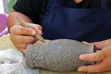Obraz premium Pottery is the process of forming vessels and other objects with clay and other ceramic materials, which are fired at high temperatures to give them a hard, durable form. Factory worker created themse