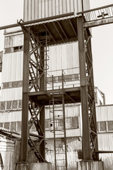 Old, abandoned concrete plant with iron rusty tanks and metal structures. The crisis, the fall of the economy, stop production capacity led to the collapse. Global catastrophe. Old photo effect
