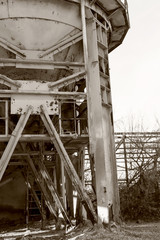 Old, abandoned concrete plant with iron rusty tanks and metal structures. The crisis, the fall of the economy, stop production capacity led to the collapse. Global catastrophe. Old photo effect