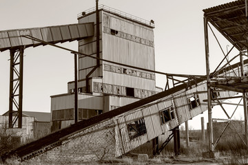 Old, abandoned concrete plant with iron rusty tanks and metal structures. The crisis, the fall of the economy, stop production capacity led to the collapse. Global catastrophe. Old photo effect