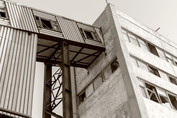 Obraz premium Old, abandoned concrete plant with iron rusty tanks and metal structures. The crisis, the fall of the economy, stop production capacity led to the collapse. Global catastrophe. Old photo effect