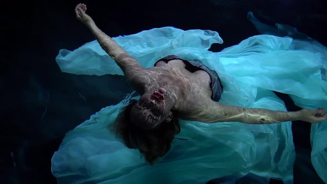 woman is diving under water face up, top view, hold breathing, sexy lady
