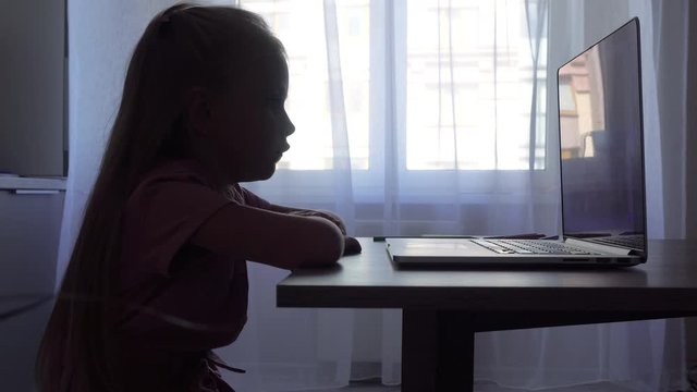 Silhouette of a little girl at the computer
